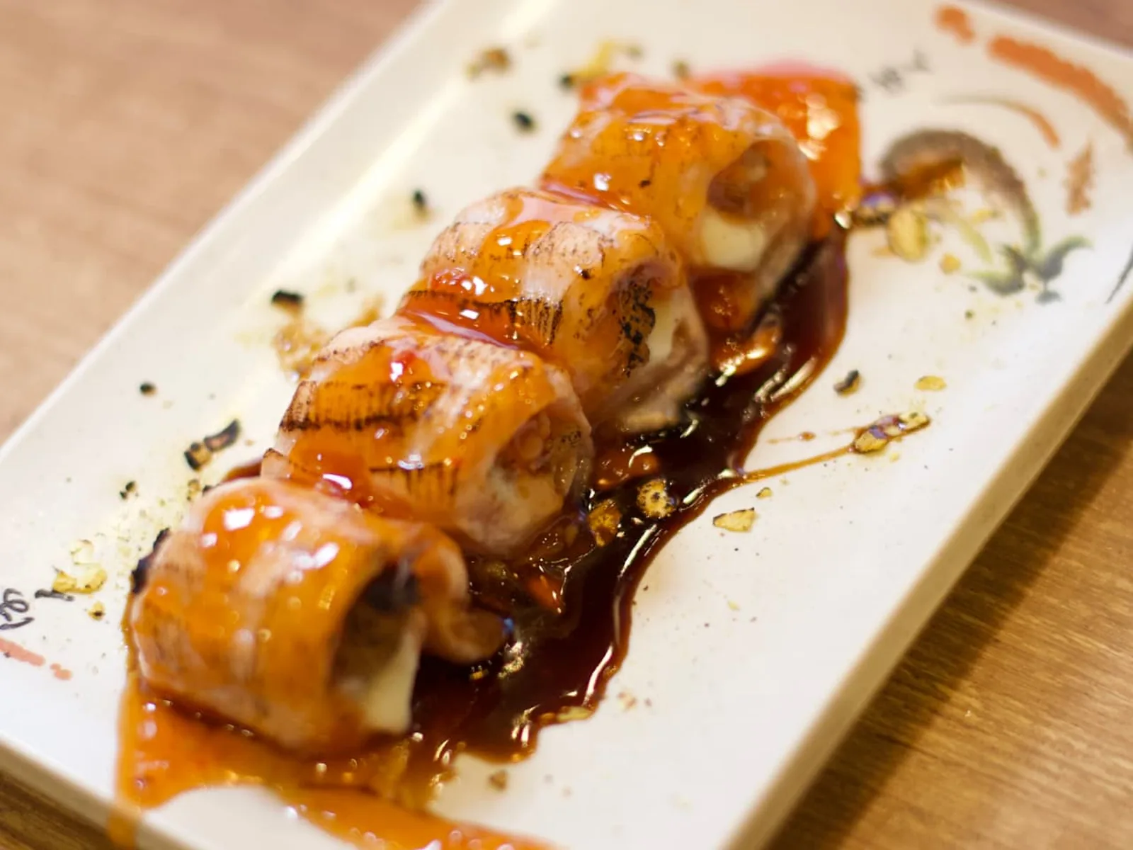 Hot rolls maçaricados cobertos com molho e cebolinha no Nuboa Sushi